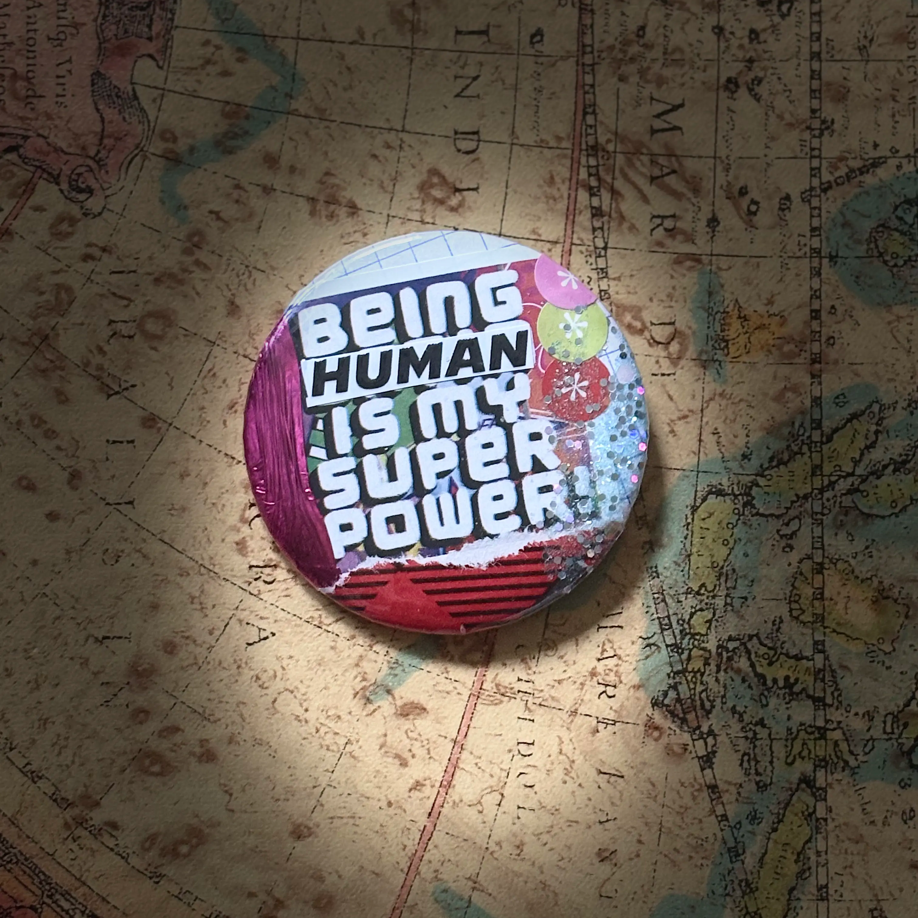 Brightly colored collage pin that reads Being Human Is My Super Power